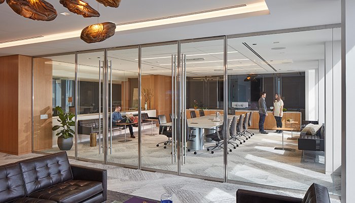 The new Draper and Kramer, Incorporated boardroom at their new corporate office at 55 E. Monroe as seen from the waiting area looking in through the glass doors with a few people talking inside.