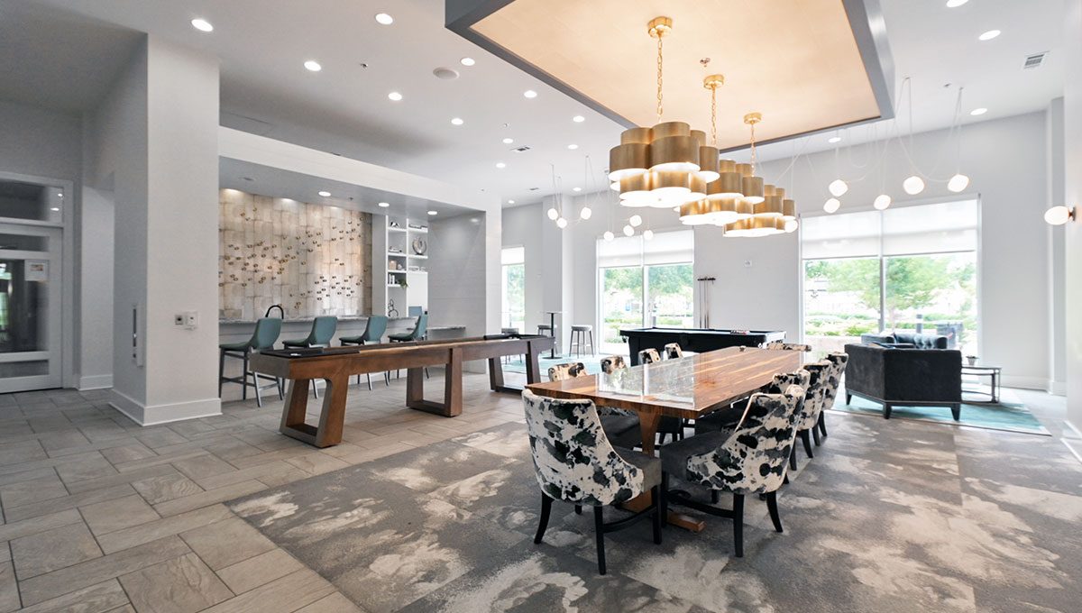 Modern open-concept room with large dining tables, stylish chairs, a pool table, and multiple contemporary light fixtures. Large windows brighten the space, and the floor is mostly tiled.