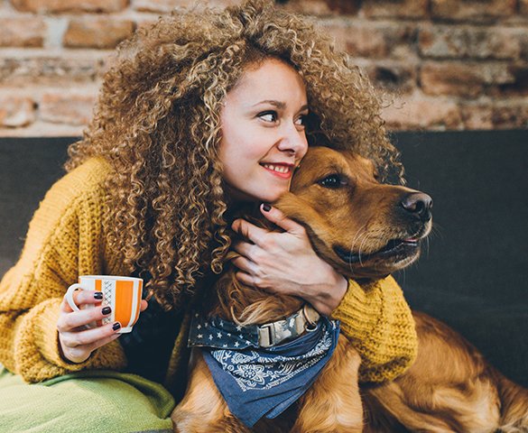 A woman hugs her dog at home.