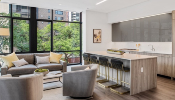 A living room at 61 Banks Street apartments with chairs and coffee table to the left and kitchen counter and stools to the right.