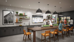 A group of friends stand around a large counter area with the catering kitchen behind them.