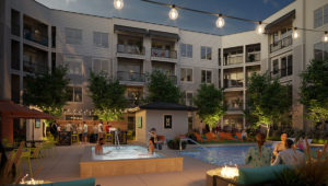 Standing in the fire pit area at dusk in the courtyard at Moda at The Hill. The hot tub and pool are just ahead with the grilling area beyond. The apartment building rises behind.