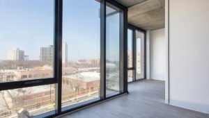 Looking out the floor-to-ceiling windows within an open unit at Aspire Residences. Buildings can be seen out the windows.