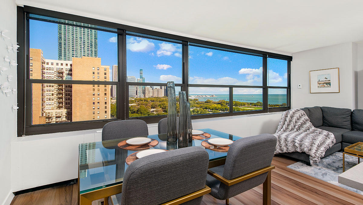 Looking across the dining room, out the windows of a residence at Eleven Thirty. Buildings in the Chicago skyline are seen outside to the left, while Grant Park and Lake Michigan are seen to the right.