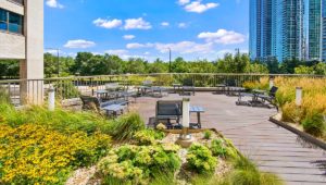 Pretty flowers surround a sitting area on the Eleven Thirty sundeck. Grant Park is seen over the balcony on a sunny day.
