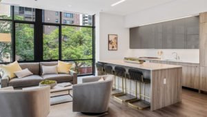 A living room at 61 Banks Street apartments with chairs and coffee table to the left and kitchen counter and stools to the right.