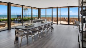 A long dining table and chairs sits in the the resident lounge at 61 Banks Street. Floor to ceiling windows show views of the outdoor terrace and Lake Michigan.