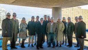 The Draper and Kramer team standing together wearing hard hats in an unfinished amenity space under construction at the Aspire Residences topping off in December 2019.