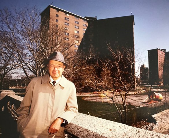 A historic portrait of Ferd Kramer standing in front of buildings.