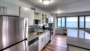 A kitchen at 1350 North Lake Shore with white cabinets and stainless steel appliances. Lake Michigan is seen out the windows.