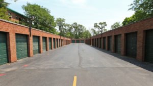 A row of red brick garages at Homestead Apartments. Garages are on both sides and have green doors.