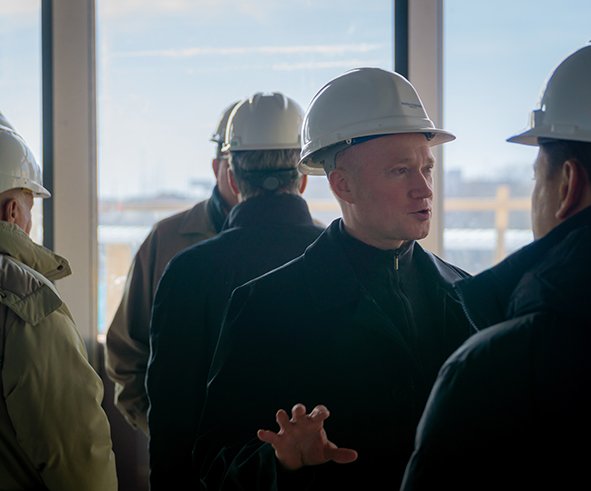 A man in a hard hat speaks to a group touring Aspire Residences while under construction during the Topping Off ceremony.