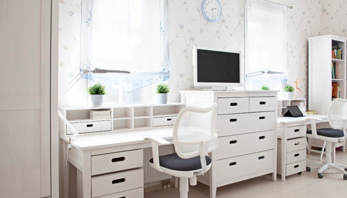 A home office setup with a large white desk, dresser and book shelf.