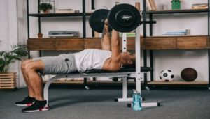 A man does a bench press with his weights at home.