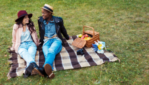 A young couple has a picnic in a grassy field.