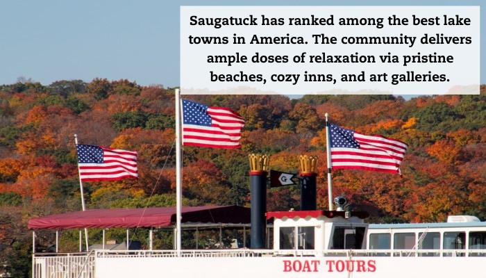 A boat tours boat flying several American flags with fall trees in the background.