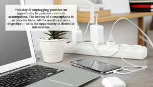 A close-up of a desk with a number of electronic devices sitting on it all plugged into a power strip. A quote reads: "This day of unplugging provides an opportunity to question common assumptions. The beauty of a smartphone is at once its bane. All the world is at your fingertips — so is the opportunity to drown in information."