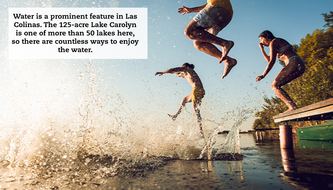 A group of friends jumping off a dock into a lake at sunrise. A caption reads, "Water is a prominent feature in Las Colinas. The 125-acre Lake Carolyn is one of more than 50 lakes here, so there are countless ways to enjoy the water."
