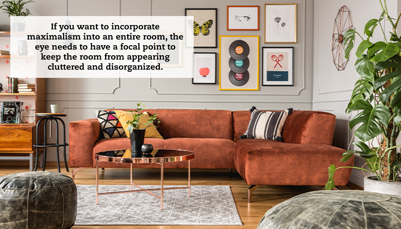 A living living with an orange sectional couch against the far wall, which has a series of pictures hanging on it. To the right is a house plant and ottoman, and to the left, a stool, smaller ottoman and a bookshelf with plants on it partially in view. A quote reads: "If you want to incorporate maximalism into an entire room, the eye needs to have a focal point to keep the room from appearing cluttered and disorganized."