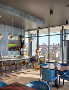 A man stands behind the bar serving a drink to a woman seated across from him in the Pub Room at Aspire.