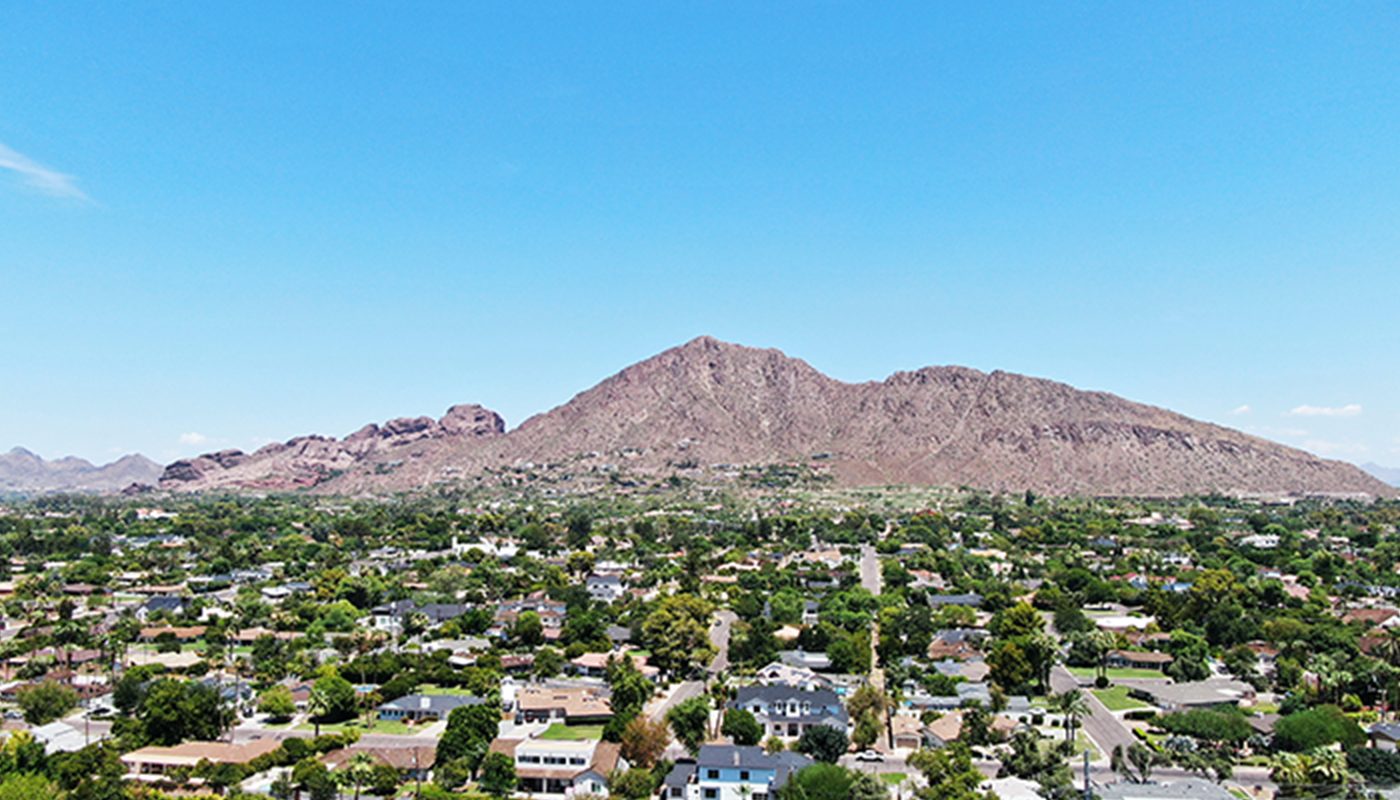 Looking across a suburban area in Phoenix from high above, a mountain is seen on the horizon.