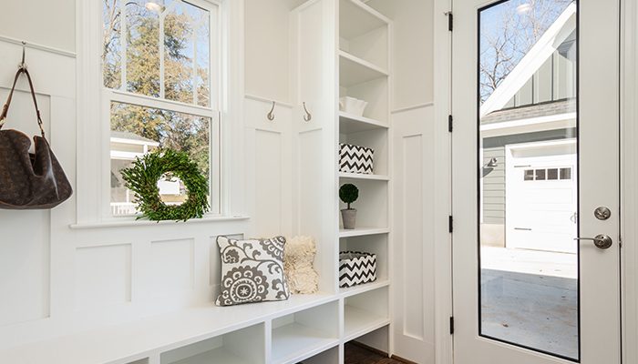 Built-in shelves adorn the left wall next to an exterior door. The garage is seen outside.