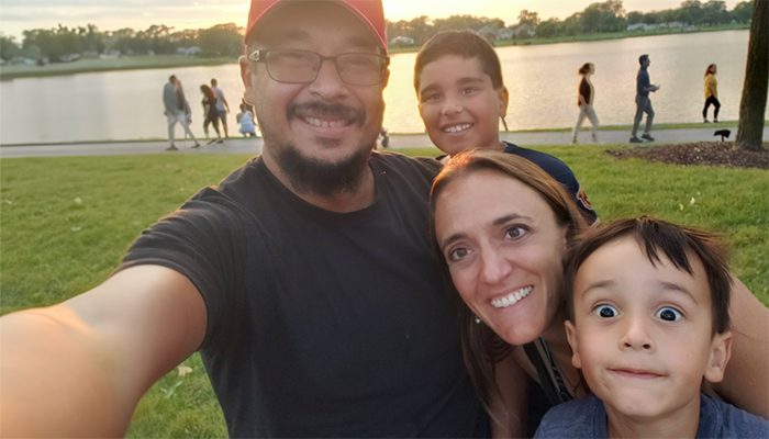 A family is taking a selfie in front of a lake.