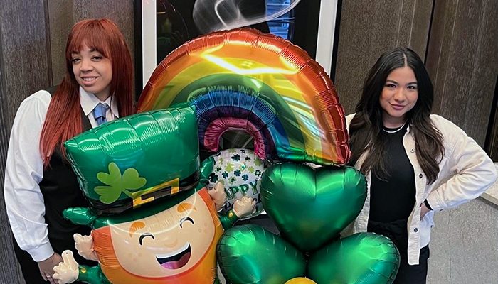 Two women posing with st patrick's day balloons.