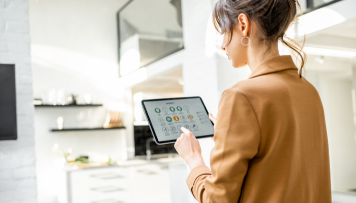 A woman using a smart home interface on a tablet in a modern kitchen.