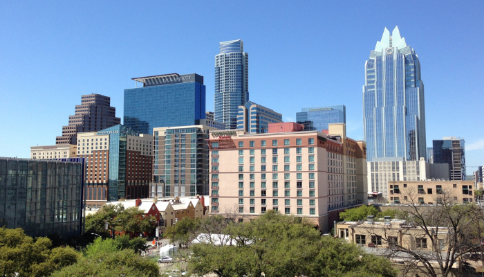 A daytime view of a downtown cityscape with a mixture of modern high-rise buildings and traditional architecture under a clear blue sky.