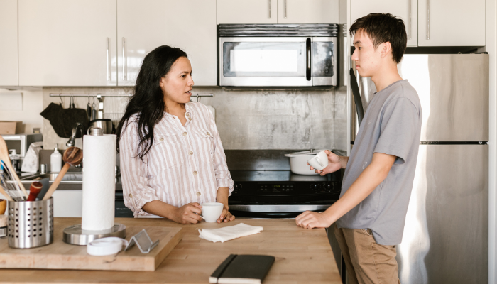 Two roommates having a serious conversation in a modern kitchen while holding coffee cups, emphasizing the importance of discussing shared responsibilities.