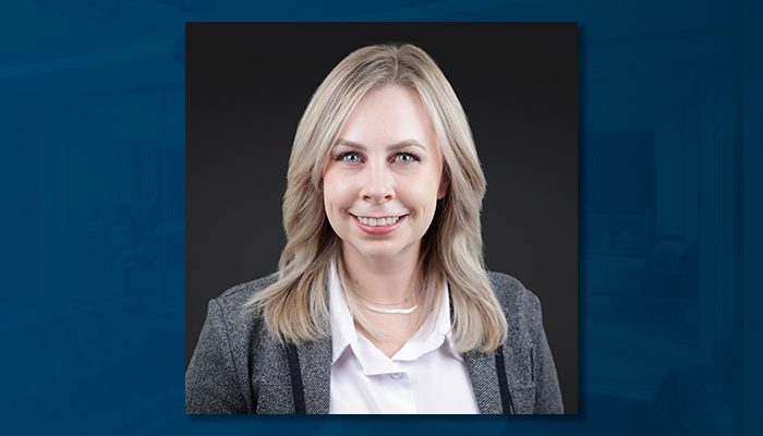 Headshot of Hannah Fischer, assistant vice president and operations manager at Draper and Kramer, Incorporated, smiling in a professional gray blazer and white blouse against a dark background.