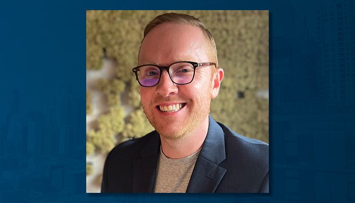 Portrait of Jeff Henderson, Senior Vice President of the Commercial Finance Group at Draper and Kramer. He is smiling, wearing glasses, a dark blazer, and a gray shirt, standing in front of a textured background.
