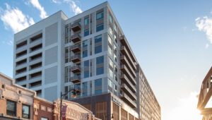 Street view of Eleven33 Apartments in downtown Oak Park with nearby restaurants, shops, and CTA station under evening light.