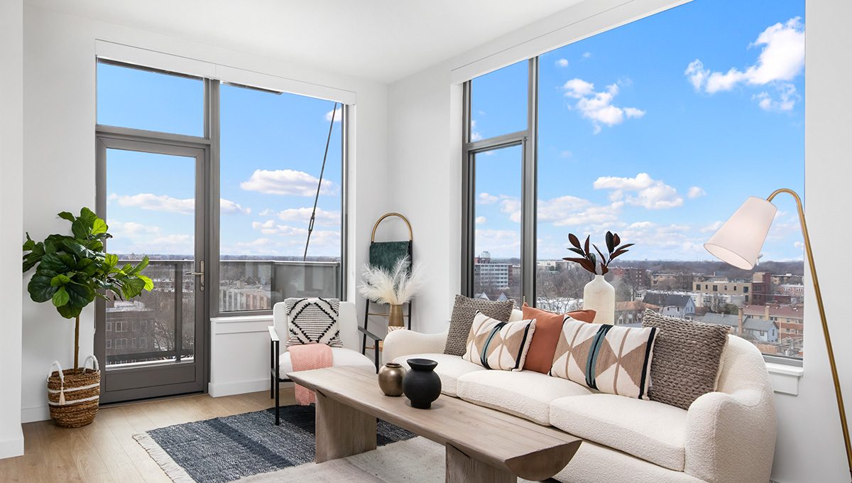 Bright living room at Eleven33 Apartments in Oak Park featuring large windows, private balcony access, and skyline views.