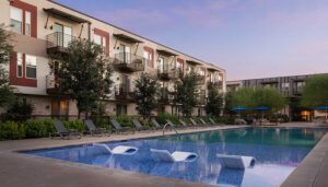Resort-style pool with lounge chairs and modern apartment buildings at DK Riata, a Draper and Kramer property.