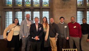 Group photo of Draper and Kramer management team members standing together at an industry event inside a historic building with large stained-glass windows.