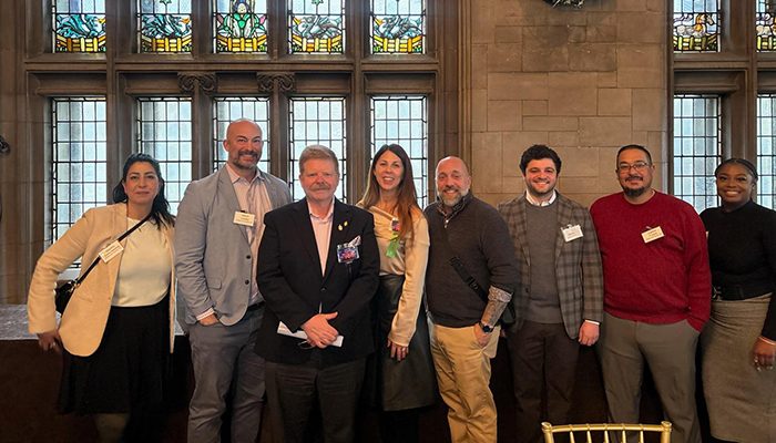 Group photo of Draper and Kramer management team members standing together at an industry event inside a historic building with large stained-glass windows.