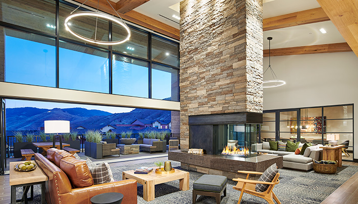 Epoque Golden great room with floor-to-ceiling windows, stone fireplace, lounge seating and expansive foothill views.